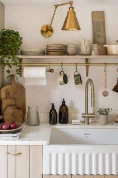 a kitchen with white counter tops and gold faucets on the shelf above the sink