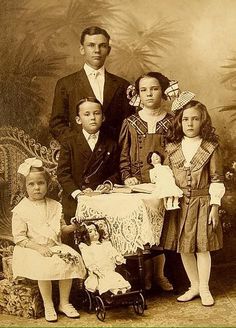 an old fashioned photo of a family posing for a picture in front of a baby's crib