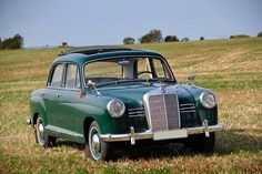 an old green car is parked in the grass