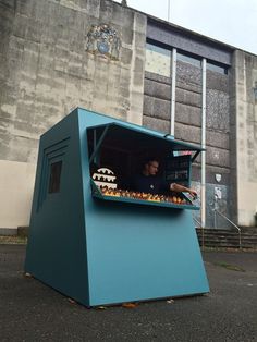 a man sitting in the back of a large blue box with food on it's sides