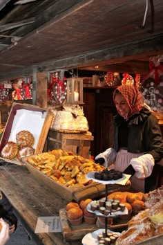 a woman standing in front of a table filled with pastries