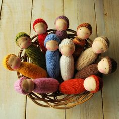 a basket filled with knitted dolls sitting on top of a wooden floor