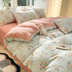 an unmade bed with pink and blue comforters, pillows and a stuffed animal