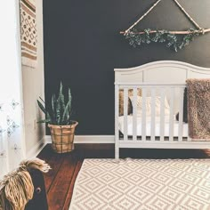 a white crib in the corner of a room next to a potted plant