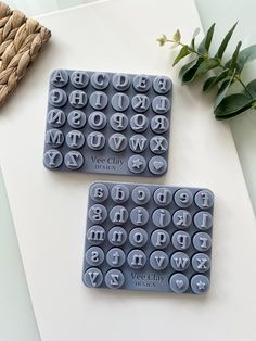 two plastic trays sitting on top of a table with letters and numbers in them