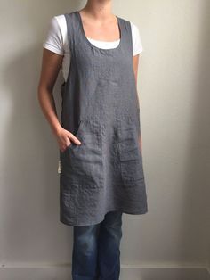 a woman standing in front of a wall wearing a gray dress and white t - shirt