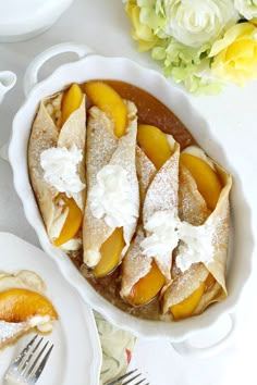 a dessert dish with peaches and powdered sugar on top, next to flowers