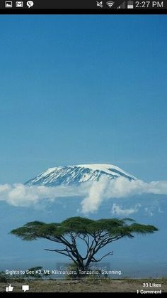 an image of a mountain in the background with clouds and trees on it's side