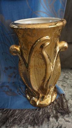 a gold vase sitting on top of a blue and white carpeted floor next to a wall