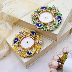 two decorative candle holders sitting on top of a white table next to flowers and candles