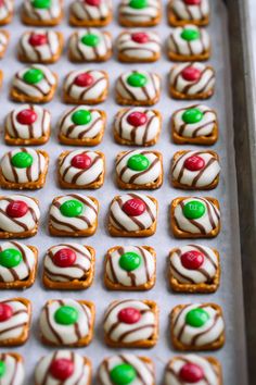 there are many decorated cookies with candy on the top one is white and has green and red candies