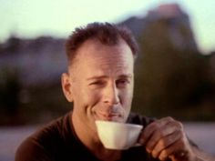 a man drinking from a white cup with his mouth wide open and looking at the camera