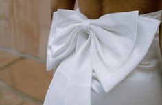 the back of a woman's white dress with a large bow