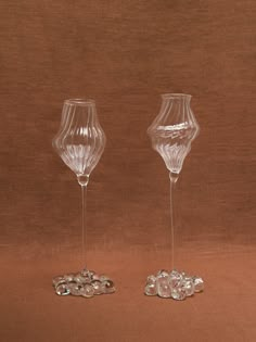 two glass goblets sitting next to each other on top of a brown surface