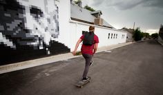 a man riding a skateboard down a street next to a wall with pixel designs on it