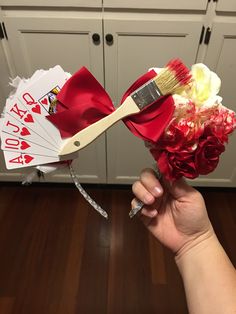 a hand holding a red and white fan with flowers on it next to a pair of scissors