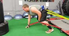 a man is doing push ups on a machine in a gym with large tires behind him