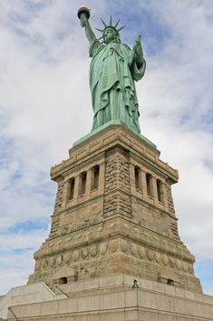 the statue of liberty stands tall in front of a cloudy sky