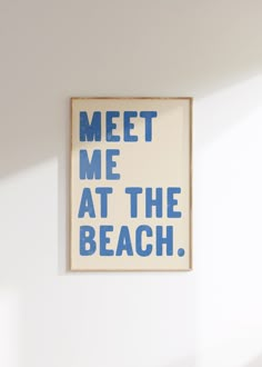 a blue and white sign that says meet me at the beach hanging on a wall