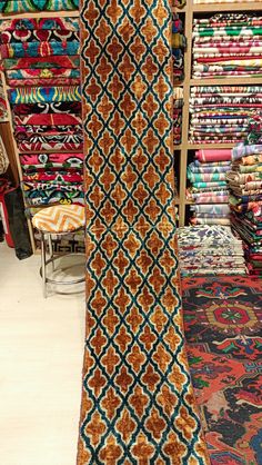 an assortment of colorful carpets and rugs in a store with shelves full of fabrics