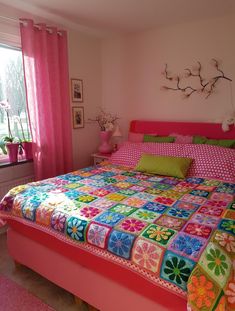 a bedroom with pink walls and colorful bedspread on the bed is decorated in bright colors