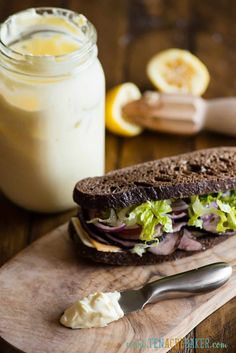 a sandwich sitting on top of a wooden cutting board next to a jar of liquid