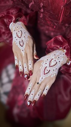 a woman with white and red nail polish holding her hands up to the camera while wearing lace gloves