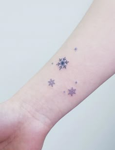 a small snowflake tattoo on the left inner arm and wrist, with stars all over it