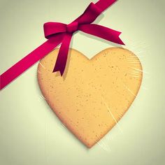 a heart shaped cookie with a red ribbon on it's side, hanging from a string