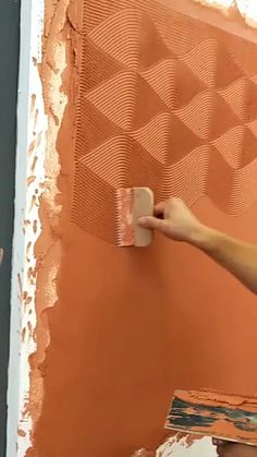 a person painting a wall with orange paint and a brown tint on the wall