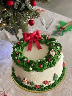 a decorated christmas cake sitting on top of a table next to a green and red wreath