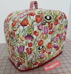 a bag with vegetables printed on it sitting on a counter top next to a red and white checkered tablecloth