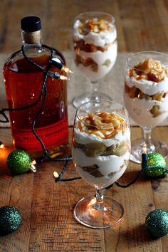 three glasses filled with desserts sitting on top of a table next to christmas decorations