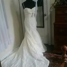 a white wedding dress is hanging on a mannequin in front of a mirror