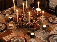 a dining room table is set with candles and dishes for thanksgiving dinner guests to enjoy