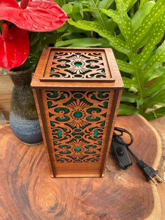 a wooden box sitting on top of a table next to a flower pot and power cord