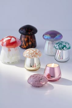 several different colored mushrooms sitting next to each other on a white surface with light coming from the top