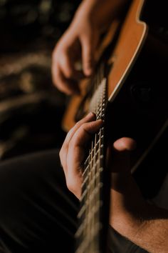 a close up of a person playing an acoustic guitar with their hands on the strings