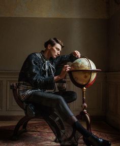 a man sitting on a chair next to a globe