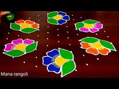 the child is playing with some colorful rangoli on the wooden table in front of them