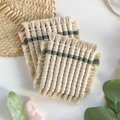 two woven baskets sitting on top of a table next to some plants and rocks with green leaves