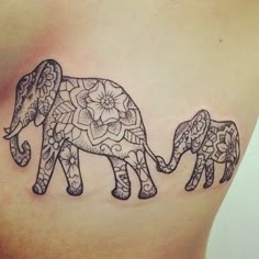 an elephant tattoo on the back of a woman's stomach with flowers and leaves