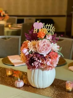 there is a white pumpkin decorated with flowers and candles on the table in front of it