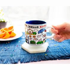 a person is holding a coffee mug on a table with oranges and confetti