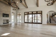 an empty living room with wood floors and chandeliers