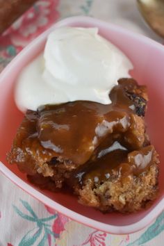 a desert with ice cream and caramel on top in a pink bowl sitting on a table