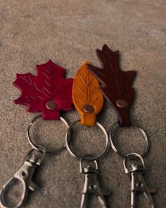 four pairs of scissors are laying on the floor next to two maple leaf shaped key chains