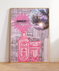 a disco ball sitting on top of a wooden floor next to a poster that says tequila