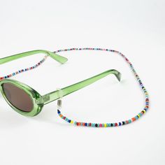 RAINBOW SUNGLASS CHAIN Introducing the must-have accessory for the sunnier months ahead! Add the Rainbow Sunglass Chain to your sunglasses for a stylish and bright splash of colour. - Made with multicoloured glass beads, rubber hoops and a silver-plated copper alloy. - Measures approx 65cm in length. - Handmade in Bali. - Sent in eco-friendly packaging - biodegradable or recyclable! - Simply slide the rubber loops over your glasses and sunglasses ear arms and pop it over your head like a necklac Sunglasses Necklace, Surf Jewelry, Sunglasses Chain, Sunglasses Strap, Beach Anklets, Bohemian Handmade, Sunglass Chain, Rattan Bag, Adjustable Jewelry