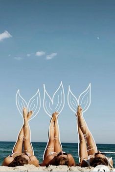 three women laying on the beach with their feet up in the air and leaves above them